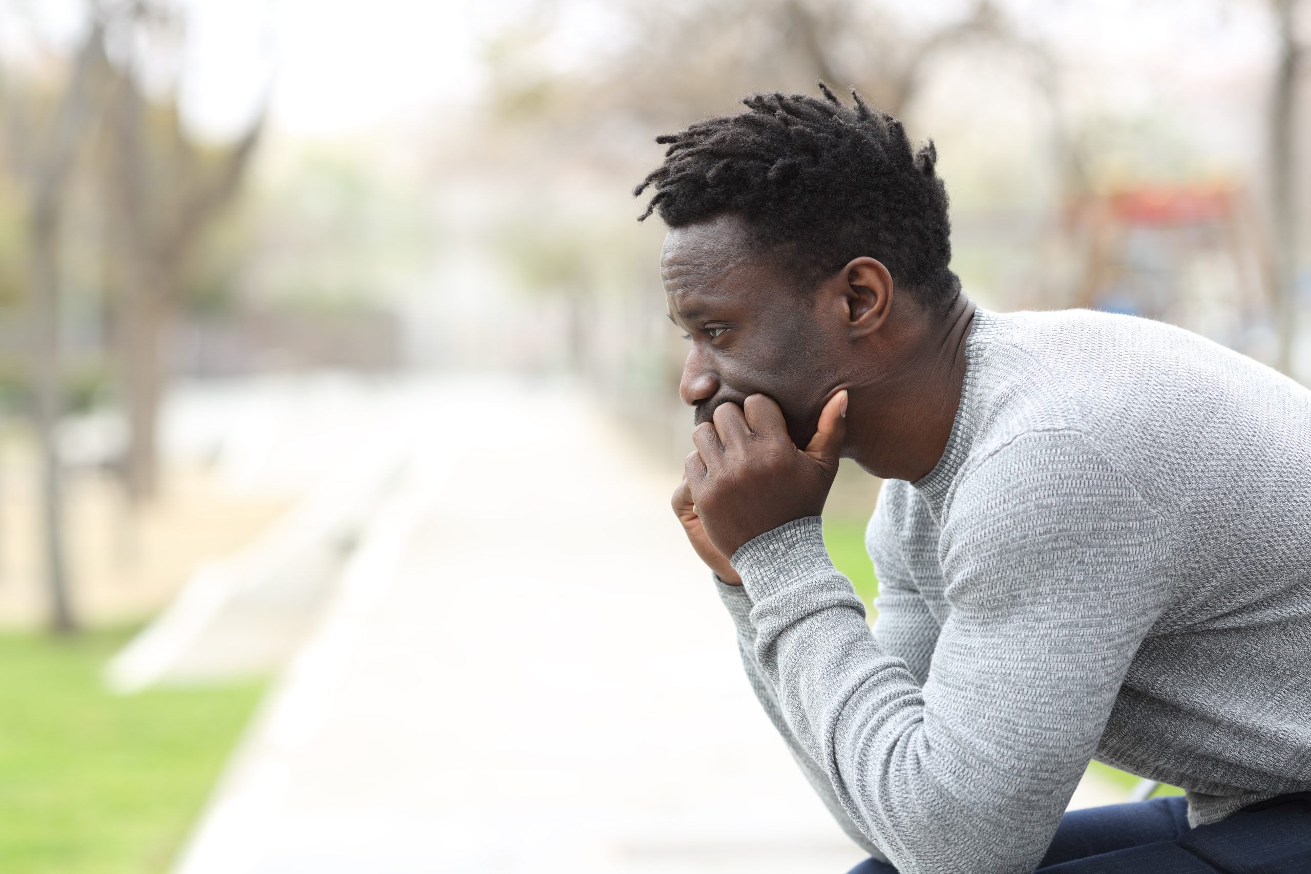 Black male sitting on a bench looking sad